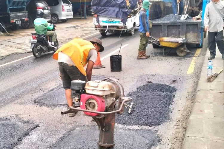 PENGECORAN : Empat lubang Jalan Raya Parung Bogor simpang gang delima, Kelurahan Bojongsari Baru, Kecamatan Bojongsari, Selasa (11/2).  (RISKY DWI LESTARI/RADAR DEPOK)