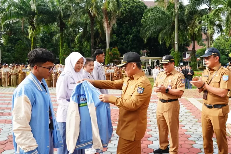 Walikota Depok, Supian Suri saat mengenakan jaket sebagai simbolis pemberangkatan 30 Duta Muda Depok ke Luar Negeri, di Halaman Balaikota Depok, Senin (24/11/2025).&nbsp; (DOKUMEN DISKOMINFO)