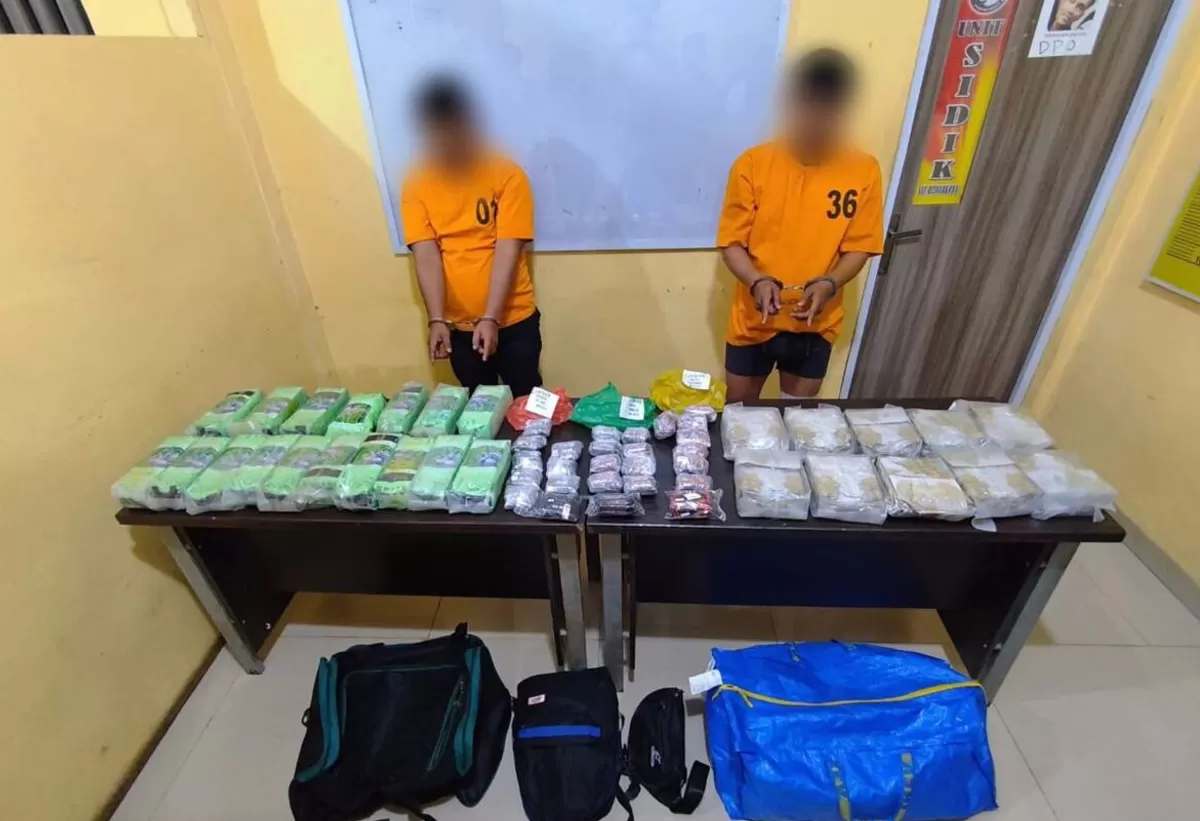 Kedua tersangka bersama barang buktinya.