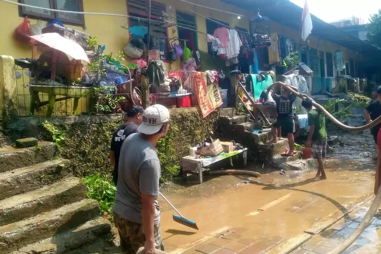 Sejumlah warga berjibaku melakukan pembersihan pasca banjir menggunakan selang air bersih dari Tagana Depok di Kelurahan Pondok Cina, Kecamatan Beji, Senin (3/03). (FOTO PRIBADI )
