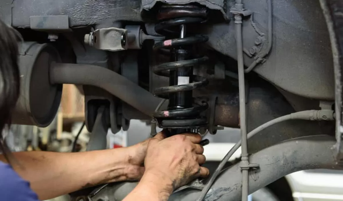 Teknisi bengkel sedang memperbaiki  shockbreaker mobil yang rusak./net