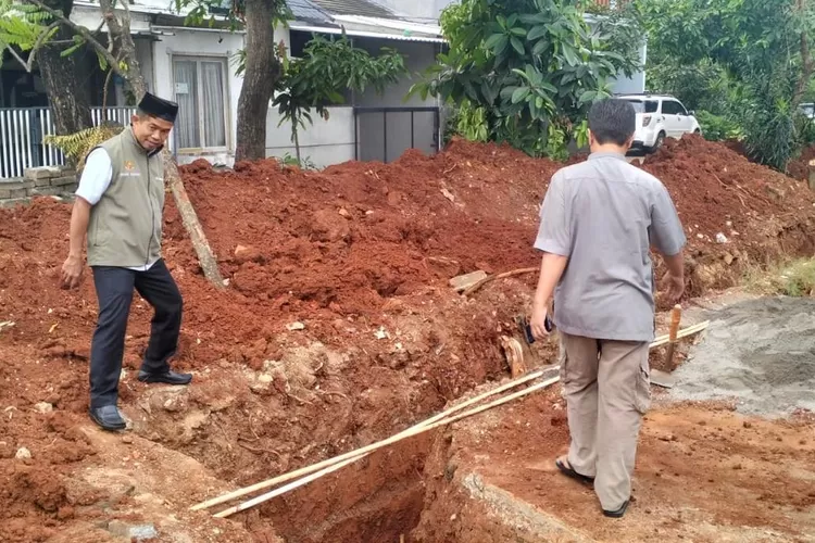 Lurah Pondok Petir Bahruddin (kiri) dan warga saat pemasangan u-ditch di Selokan Perumahan Pamulang Elok Blok Q1 RT5/14 Kelurahan Pondok Petir, Kecamatan Bojongsari, Rabu (19/2). (RISKY DWI LESTARI/RADAR DEPOK)