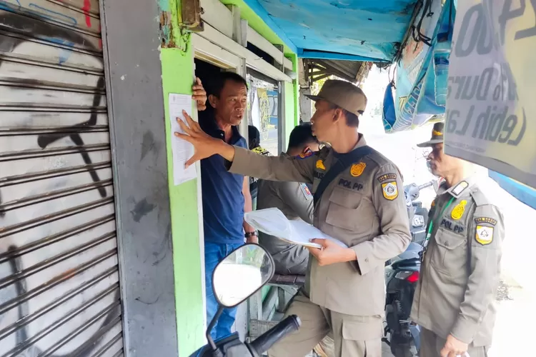 Petugas Satpol PP Kecamatan Ciawi memasang imbauan di warung pedagang agar mengosongkan bangunannya. (KABAR BOGOR)