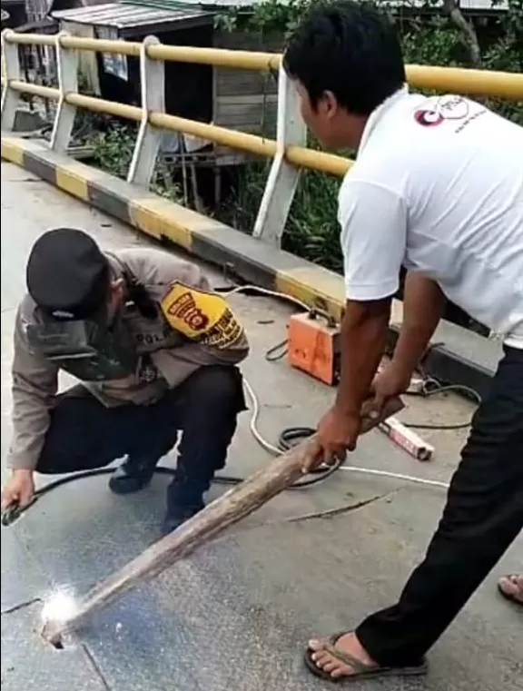 Bhabinkamtibmas Polsek Pengabuan Aipda Ucen S Kasih bersama warga memperbaiki kerusakan jembatan di Teluk Nilau (Dokumentasi Polsek Pengabuan)