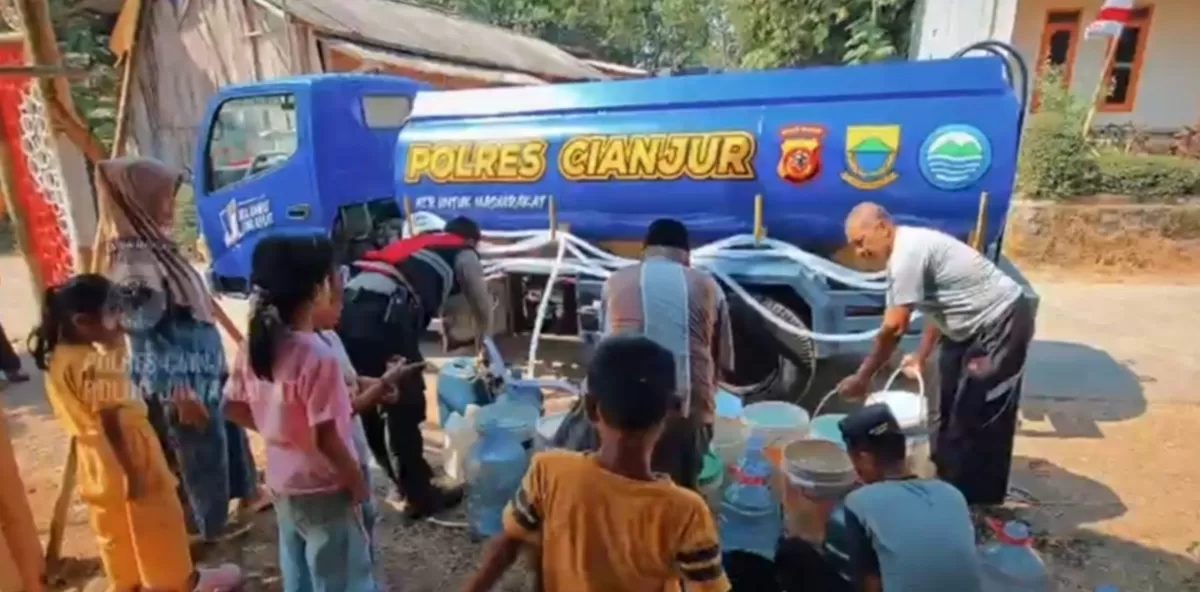 Foto: Petugas kepolisian membantu mengisikan air bersih ke wadah milik warga saat penyaluran bantuan di Kampung Cibarengkok, Desa Sukalaharja, Kecamatan Cibeber, Kabupaten Cianjur. (FOTO: Ist)