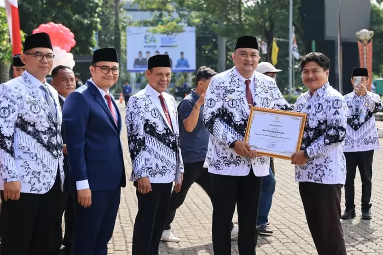 Bupati Bogor Rudy Susmanto menyerahkan penghargaan kepada insan pendidikan pada Upacara HGN 2025 di Lapangan Tegar Beriman. (Foto/Diskominfo Kabupaten Bogor.)