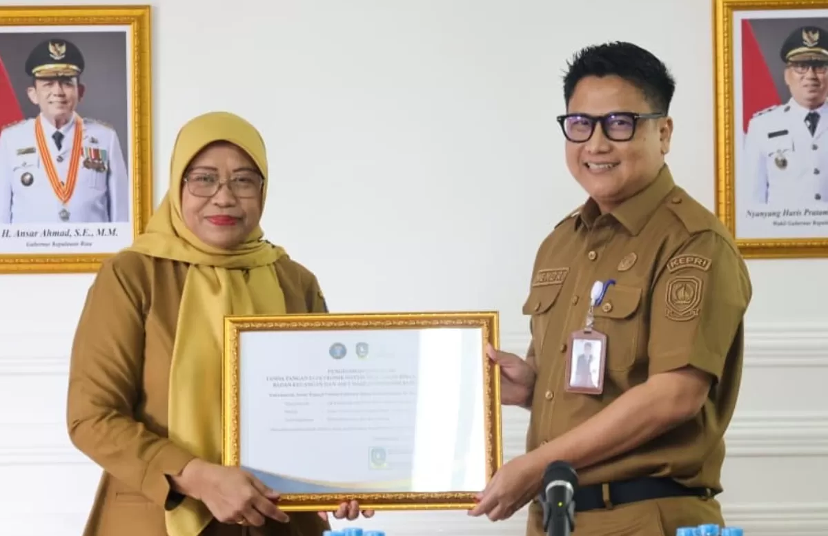 Kepala Diskominfo Kepri menyerahkan rekomendasi Integrasi TTE pada aplikasi SIPANGKAS kepada Kepala BKAD Provinsi Kepri, Venni Meitaria Detiawati, di Collaboration Room Diskominfo Kepri. (Foto: Diskominfo Kepri)